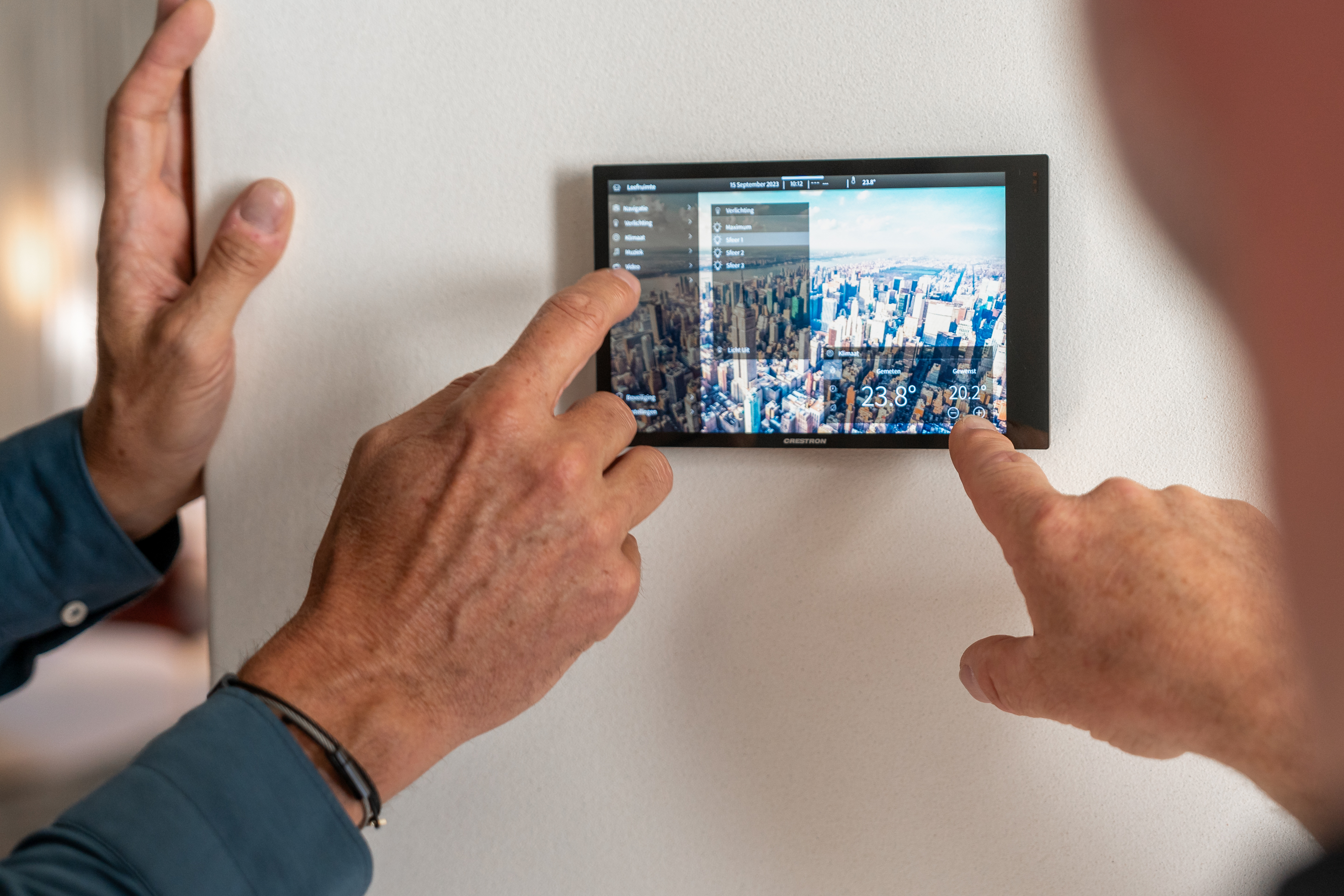 Een man past met één druk op het scherm het binnenklimaat van zijn woning aan dankzij een modern domoticasysteem.